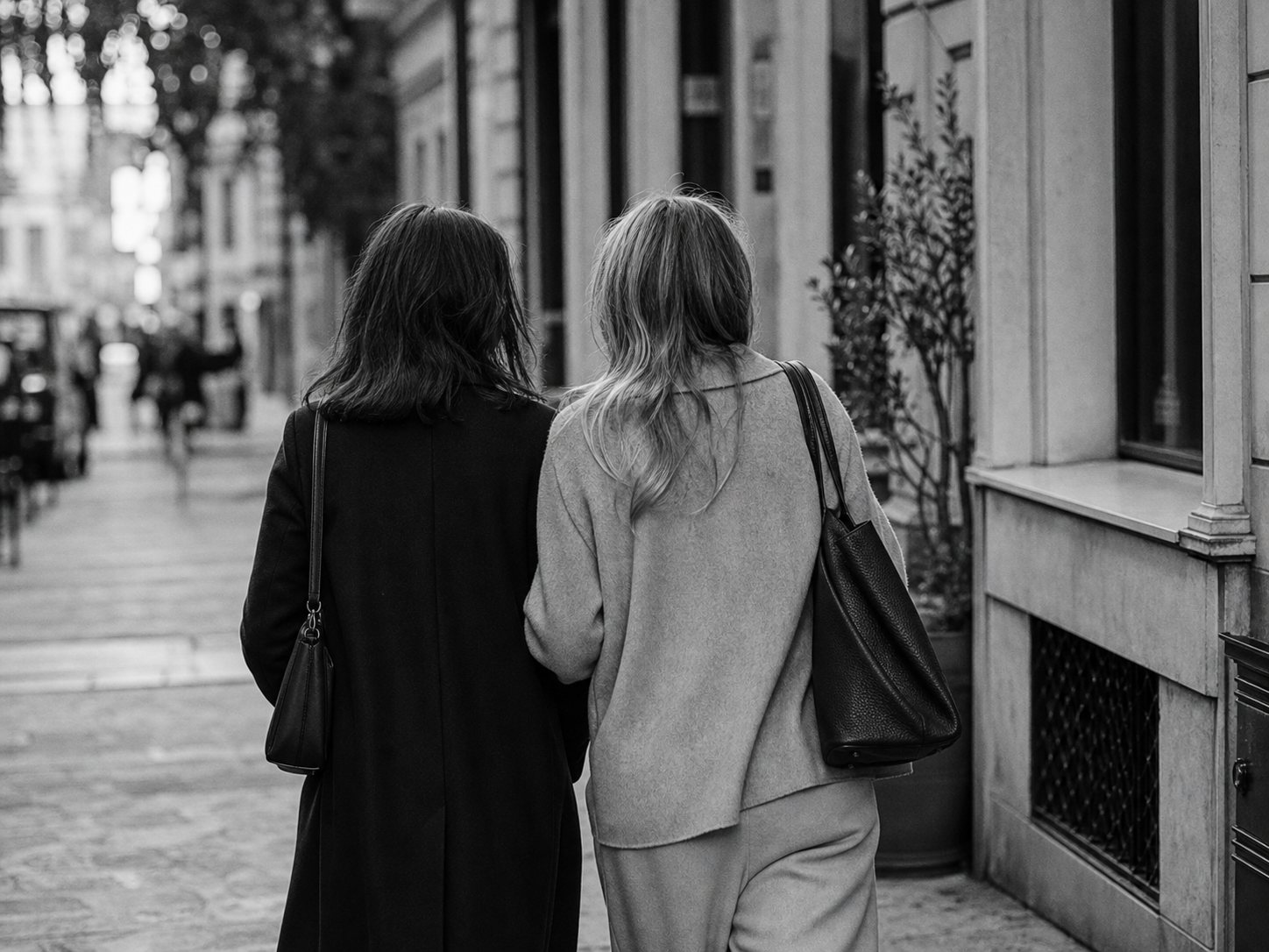 Duas mulheres vistas de costas a caminhar juntas numa rua, representando amizade adulta