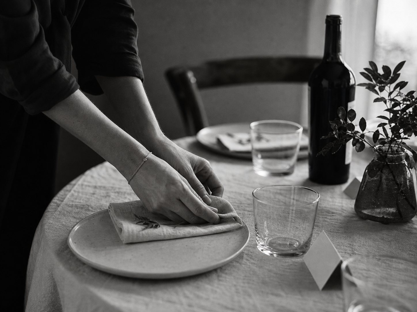 Mãos a preparar uma mesa de encontro, representando hospitalidade, acolhimento e presença
